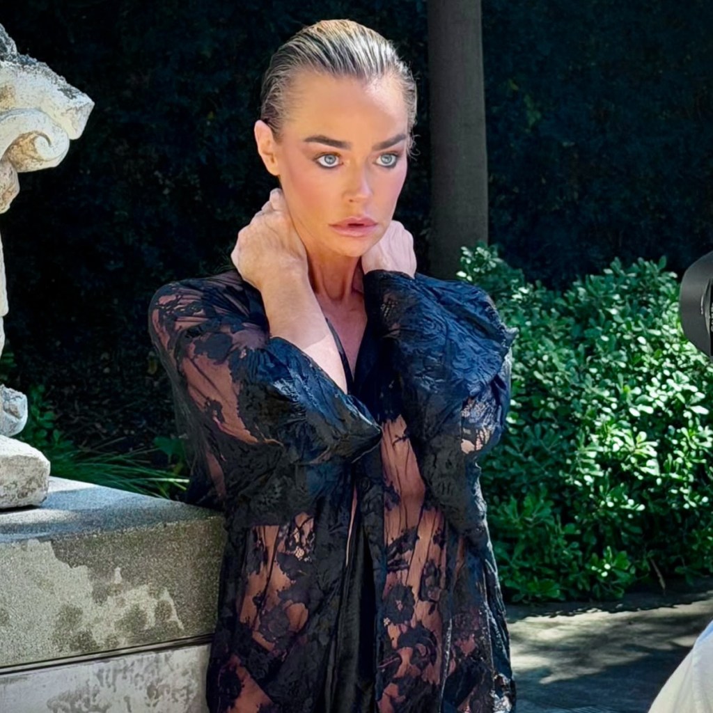Denise Richards in a black lace robe, posing outdoors with wet hair.