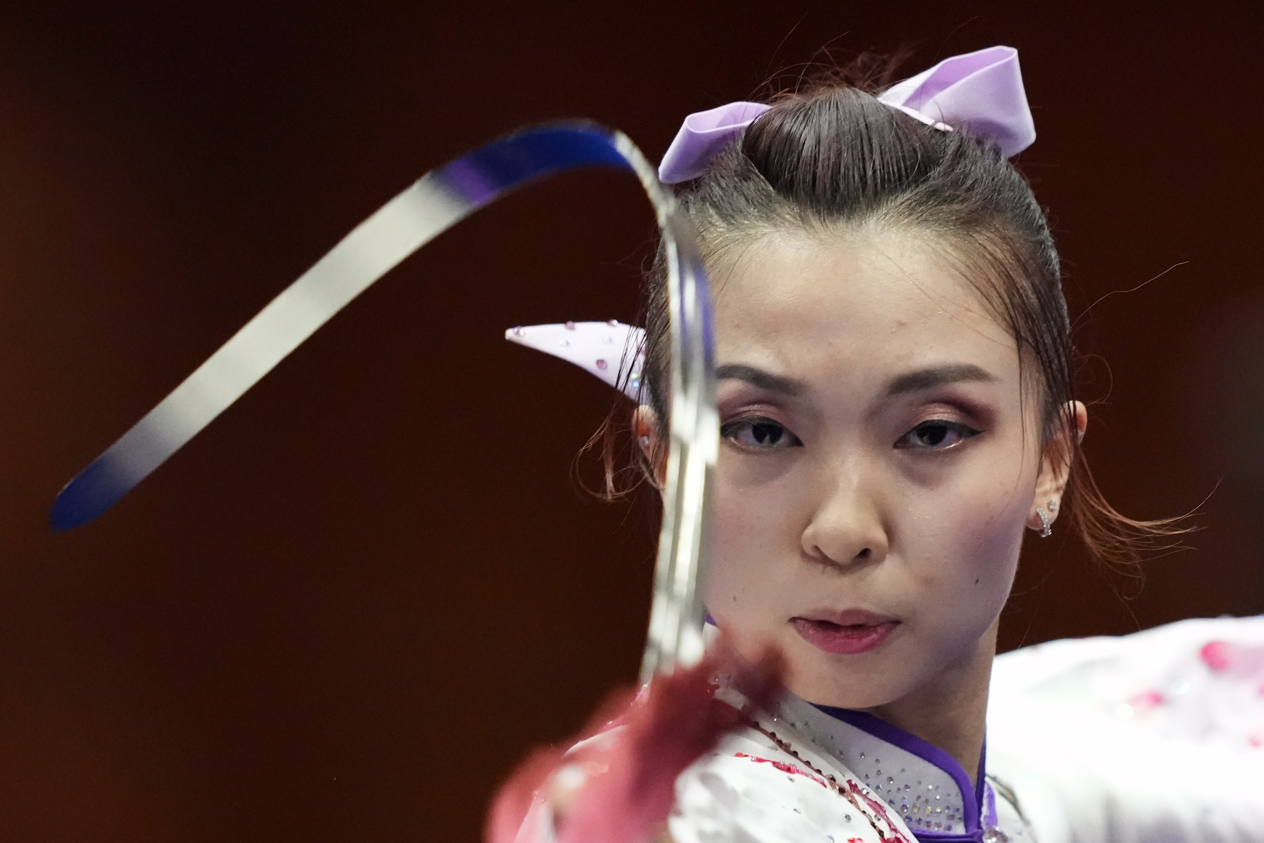 A martial artist performs, wielding a flexible blade.
