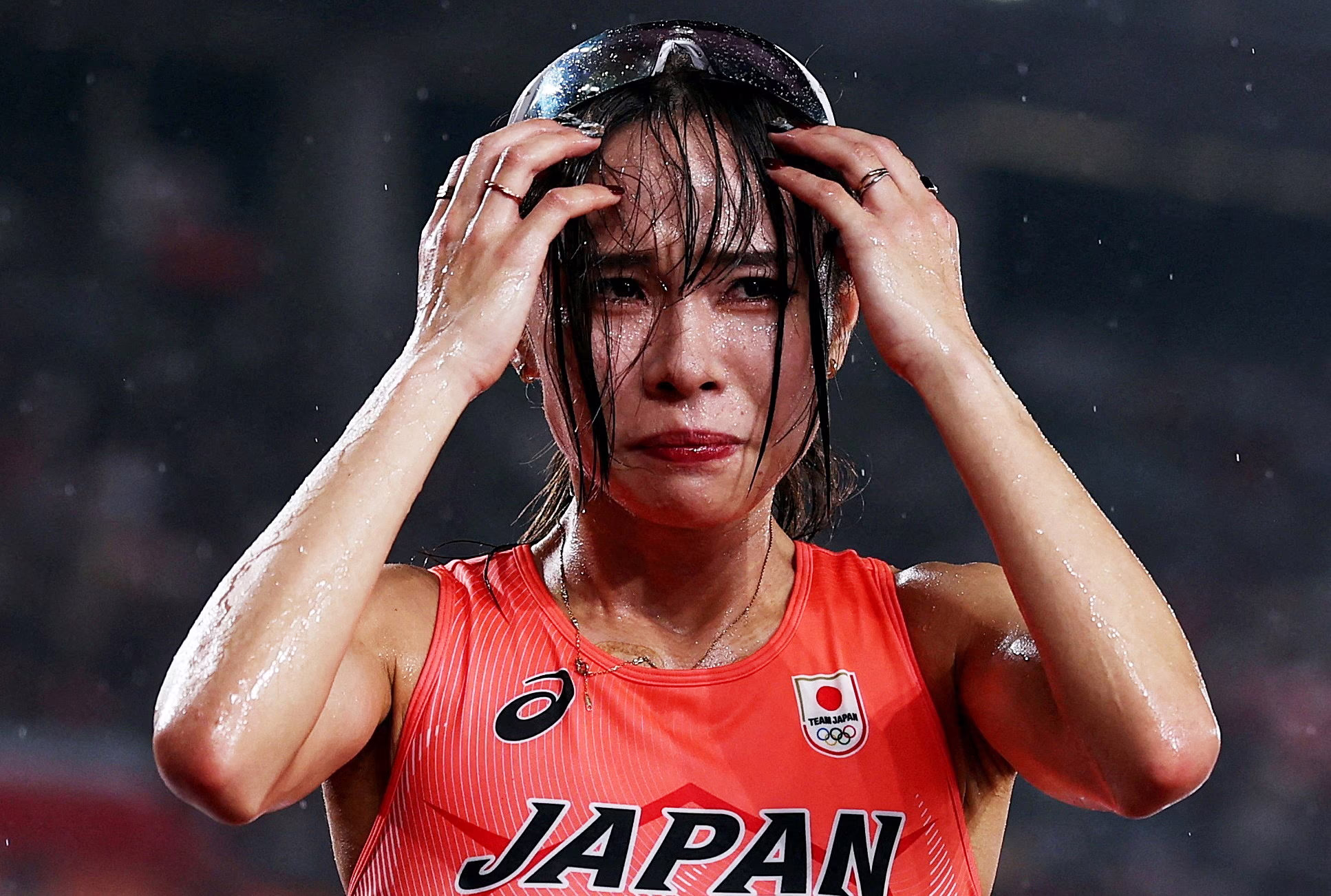A runner looks upset after a race, wet from falling rain.