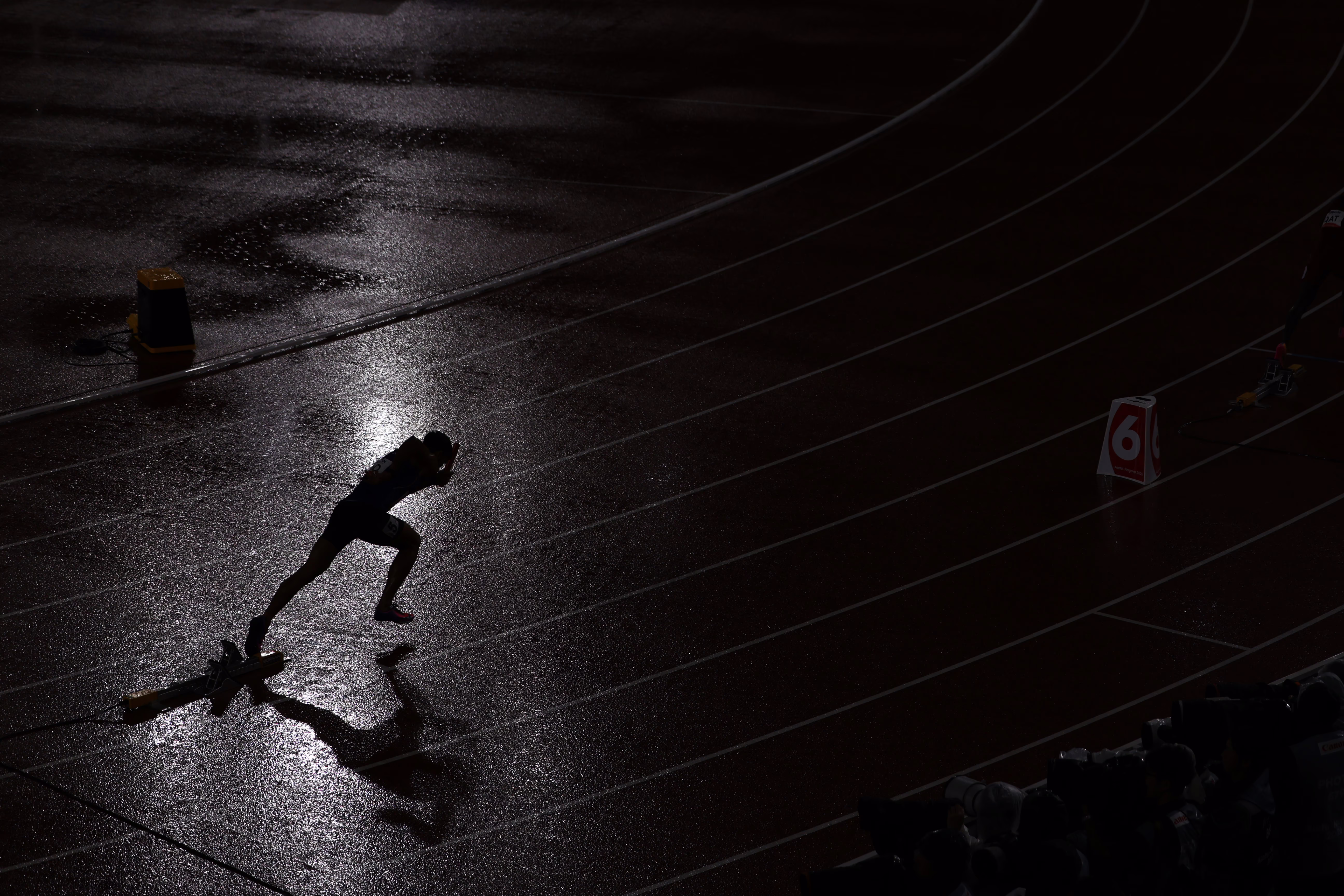 A runner starts a race, seen in silhouette on a rainy day.