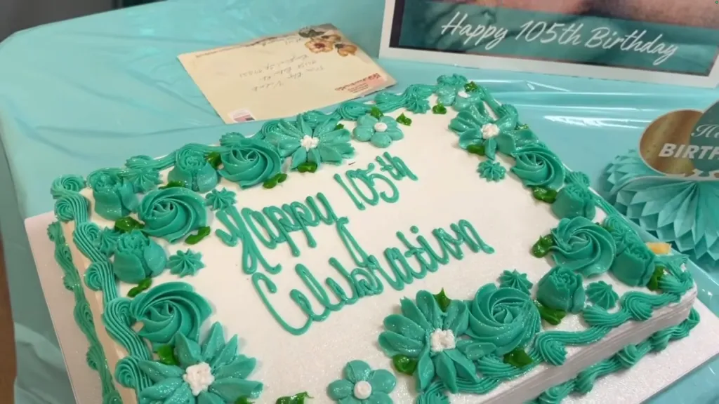 A birthday cake decorated with teal icing flowers and the words 
