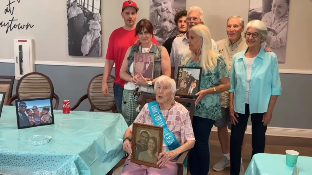 Blynda Vidock, a woman born in 1921, celebrates her 105th birthday in Baytown, Texas, surrounded by her family who hold up framed photographs.