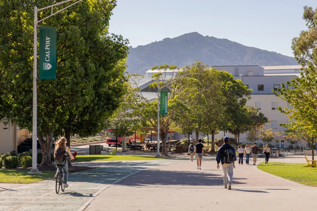 California Polytechnic State University campus with students walking and biking, and a banner that reads