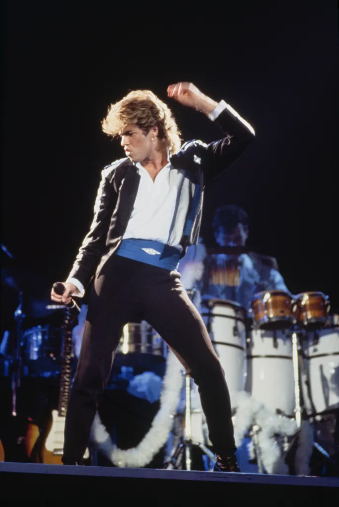 George Michael performing on stage during the Wham! 1985 world tour.