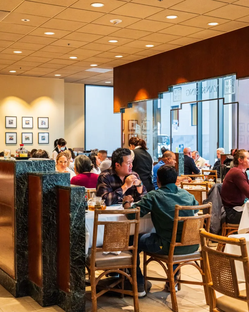 People dining in a busy restaurant, with visible Yank Sing signage.