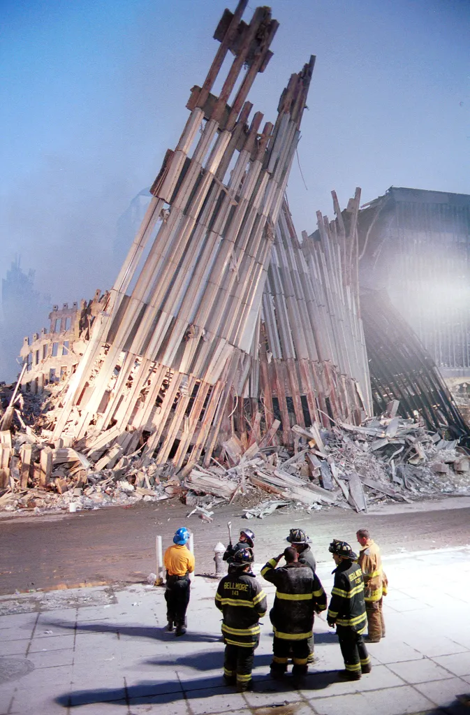 New York City firefighters stand among the rubble of the World Trade Center.