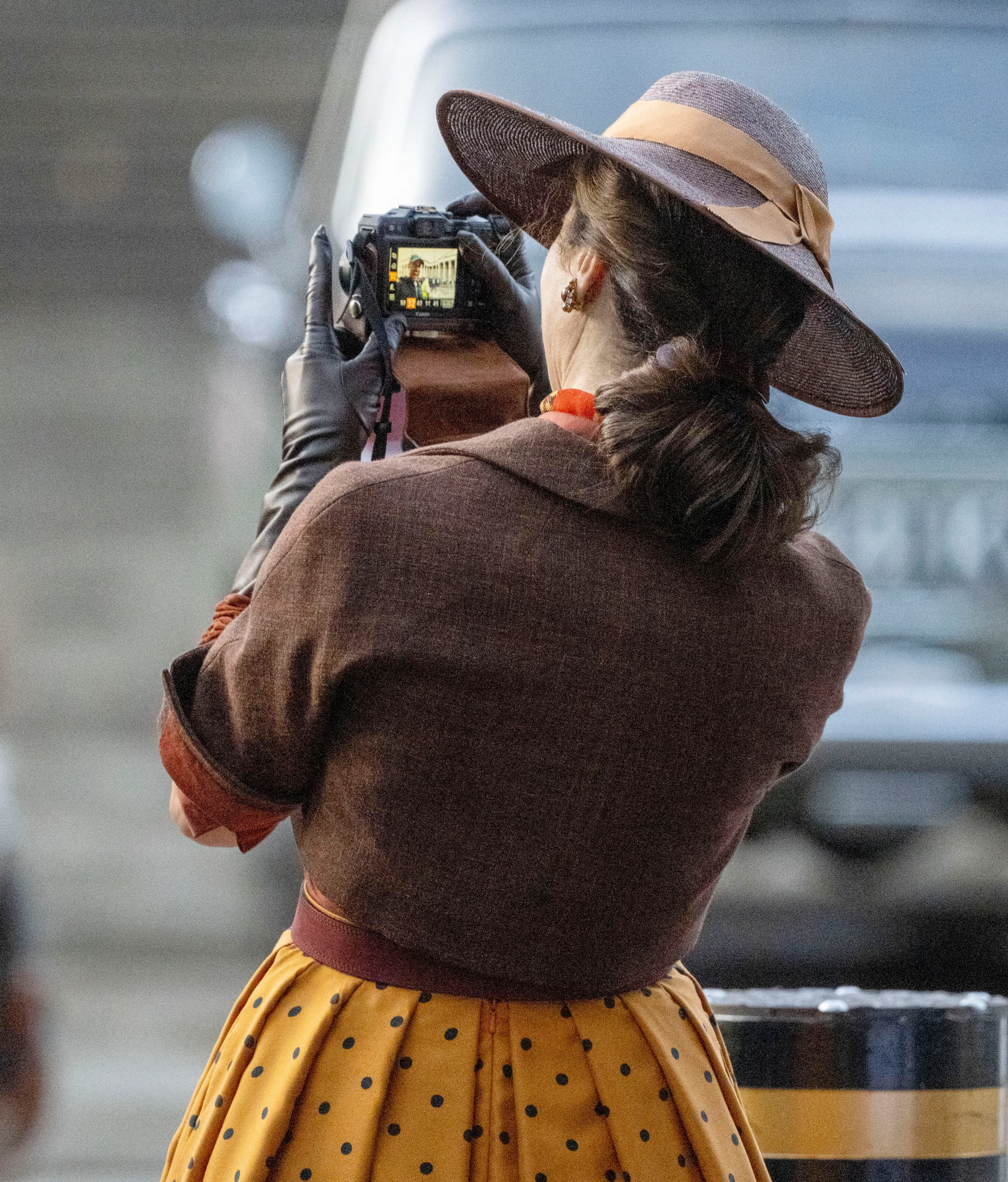 Rachel Weisz as Evelyn O'Connell in The Mummy, wearing a polka dot skirt and hat, holding a camera on set.