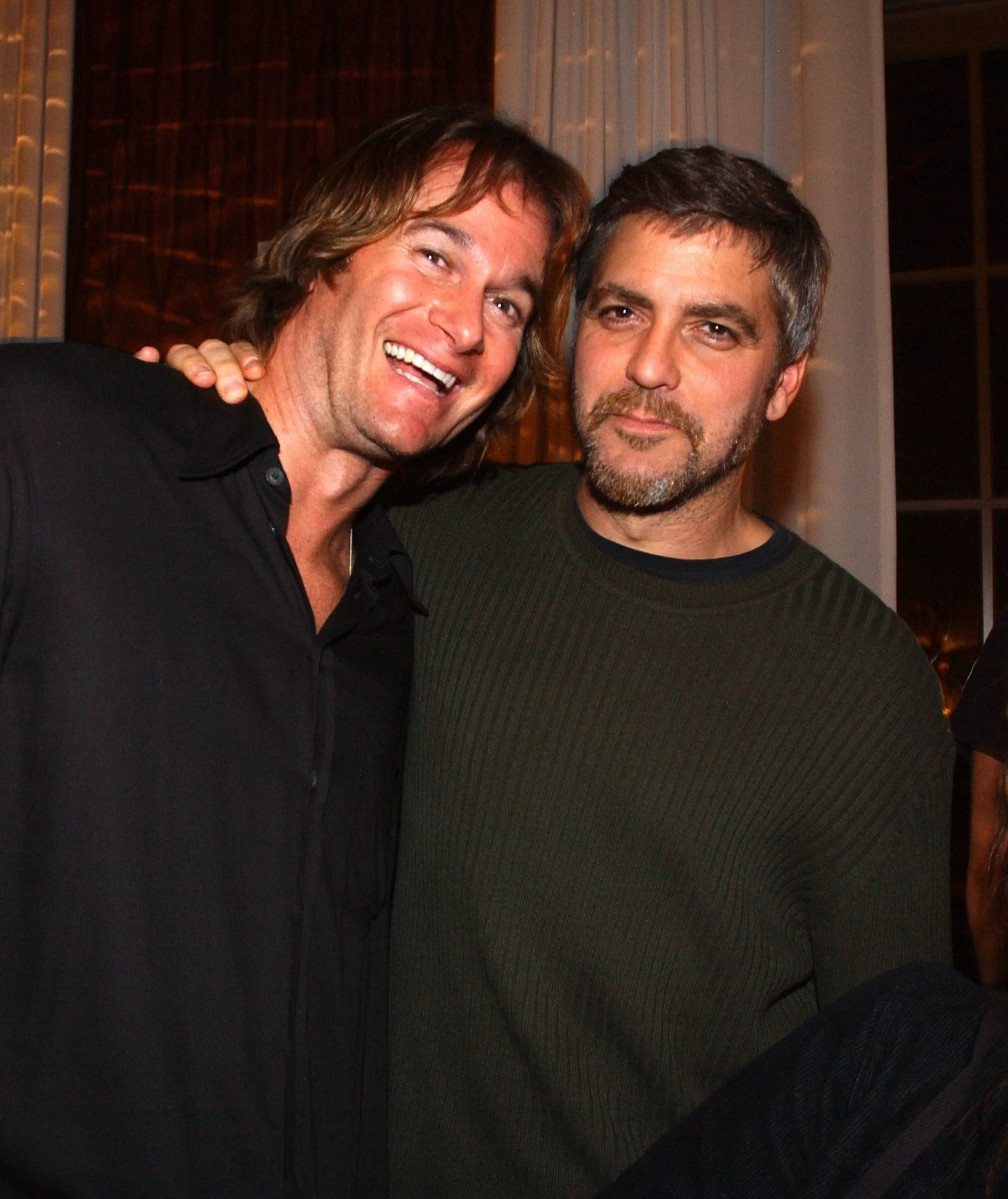 Rande Gerber and George Clooney smiling at the camera, with Gerber's arm around Clooney.