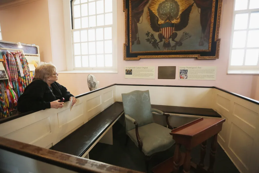A woman stands next to George Washington's pew in St. Paul's Chapel.