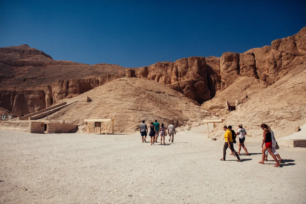 A small group of tourists walk toward the entrance to a tomb in The Valley of the Kings in Luxor, Egypt.