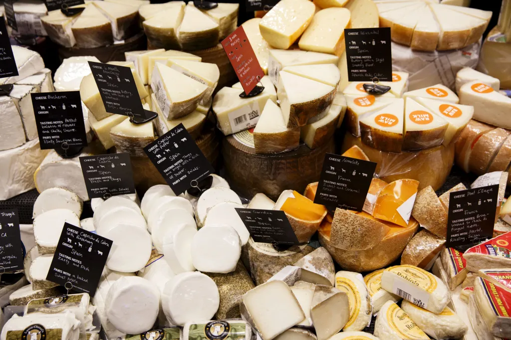 Various cheeses are displayed for sale in the specialty foods section of a Whole Foods Market.