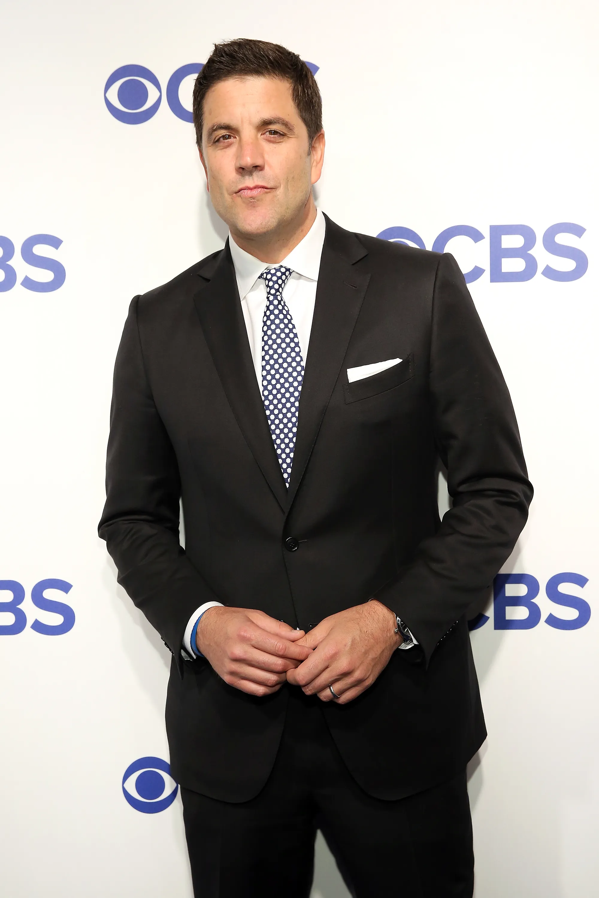 Journalist Josh Elliott wearing a black suit, blue and white polka dot tie, and white pocket square at the 2016 CBS Upfront.