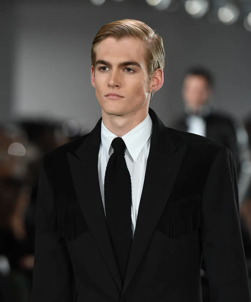 Presley Gerber modeling a black fringed jacket and black tie.