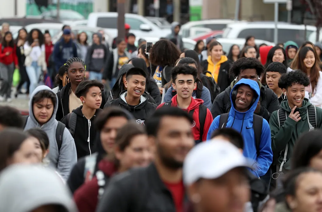 A crowd of high school students walks outside during a school walkout demonstration.