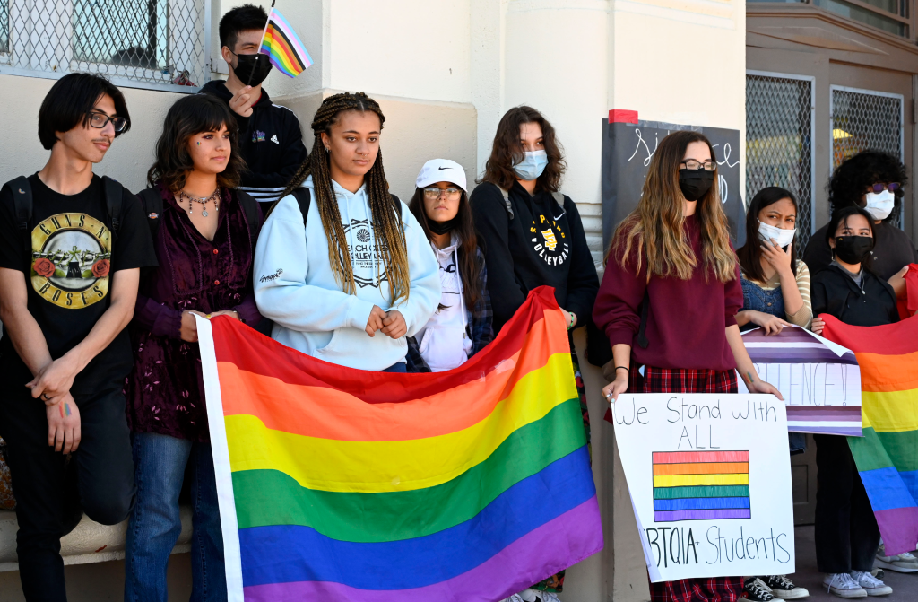 Students holding LGBTQ+ pride flags and signs in support of the LGBTQ+ community.