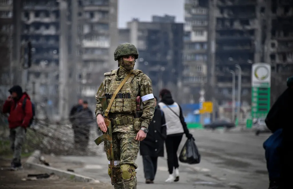 A Russian soldier with a rifle patrolling a street in Mariupol.