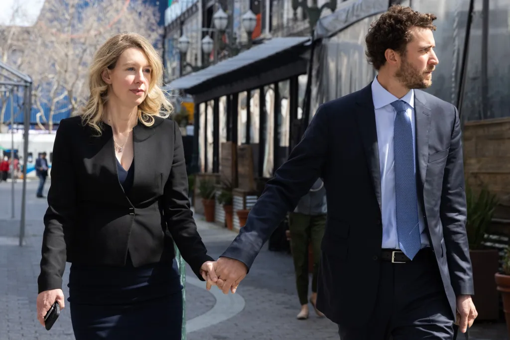 Elizabeth Holmes and Billy Evans hold hands while leaving federal court.