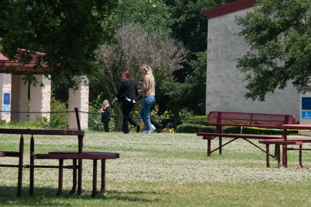 Elizabeth Holmes walking toward the Federal Prison Camp in Bryan, Texas, flanked by prison officials.