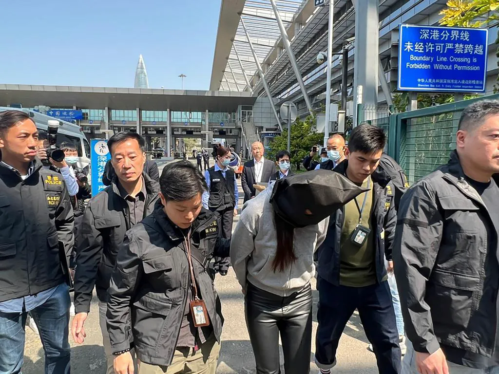 Hong Kong police escort a suspect in the killing of model Abby Choi at the Shenzhen Bay Port border crossing.