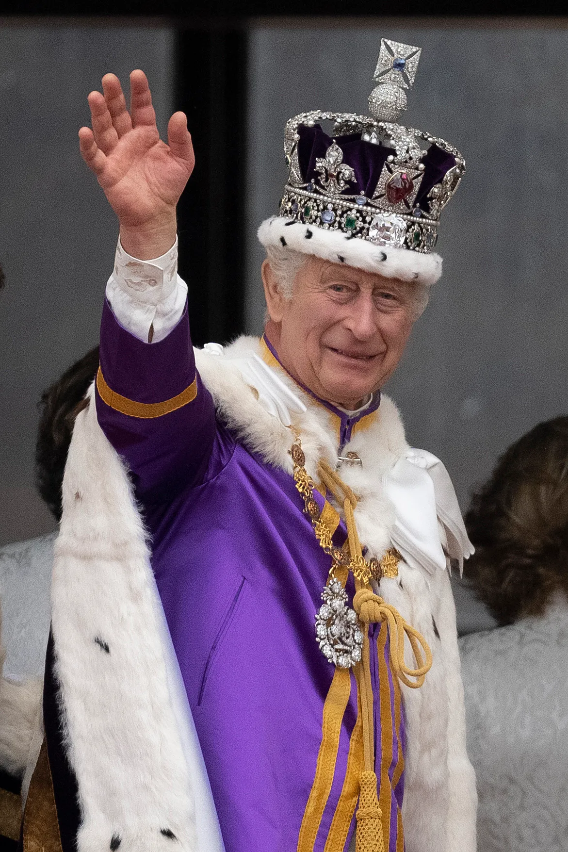 King Charles III in coronation regalia waves from the Buckingham Palace balcony.