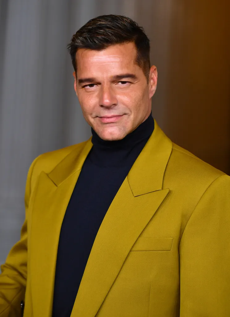 Ricky Martin wearing a gold suit jacket and black turtleneck.