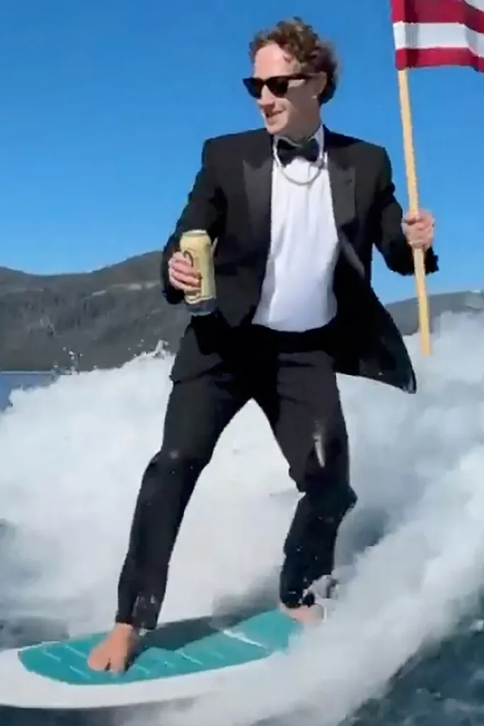 Mark Zuckerberg hydrofoiling in a tuxedo, holding a beer and an American flag.