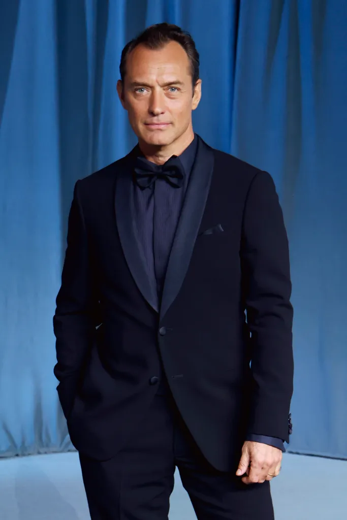 Jude Law in a black suit with a bow tie.