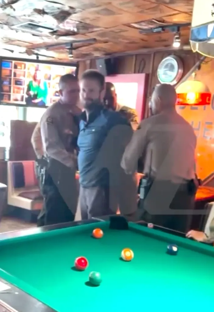 Police arresting Brian Hickerson in a bar with a pool table in the foreground.