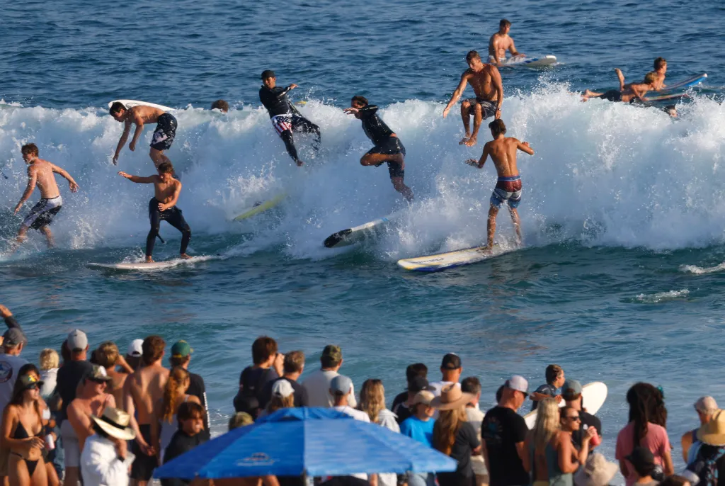 Surfers ride and wipe out on a wave during the