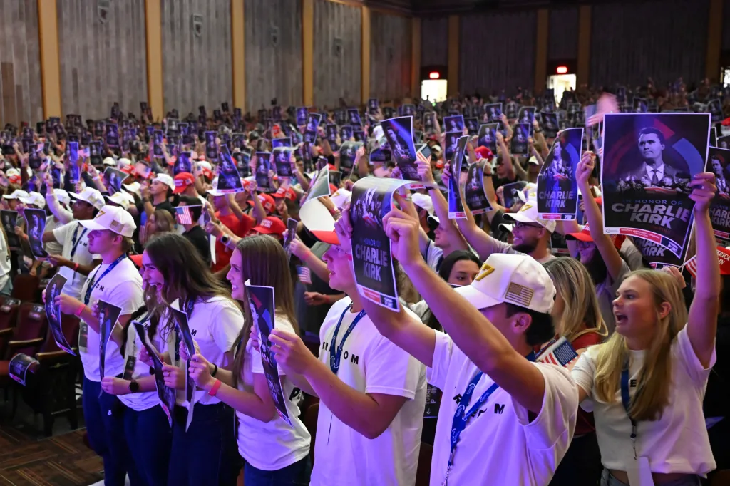 Attendees hold up posters with photos of Charlie Kirk during an 