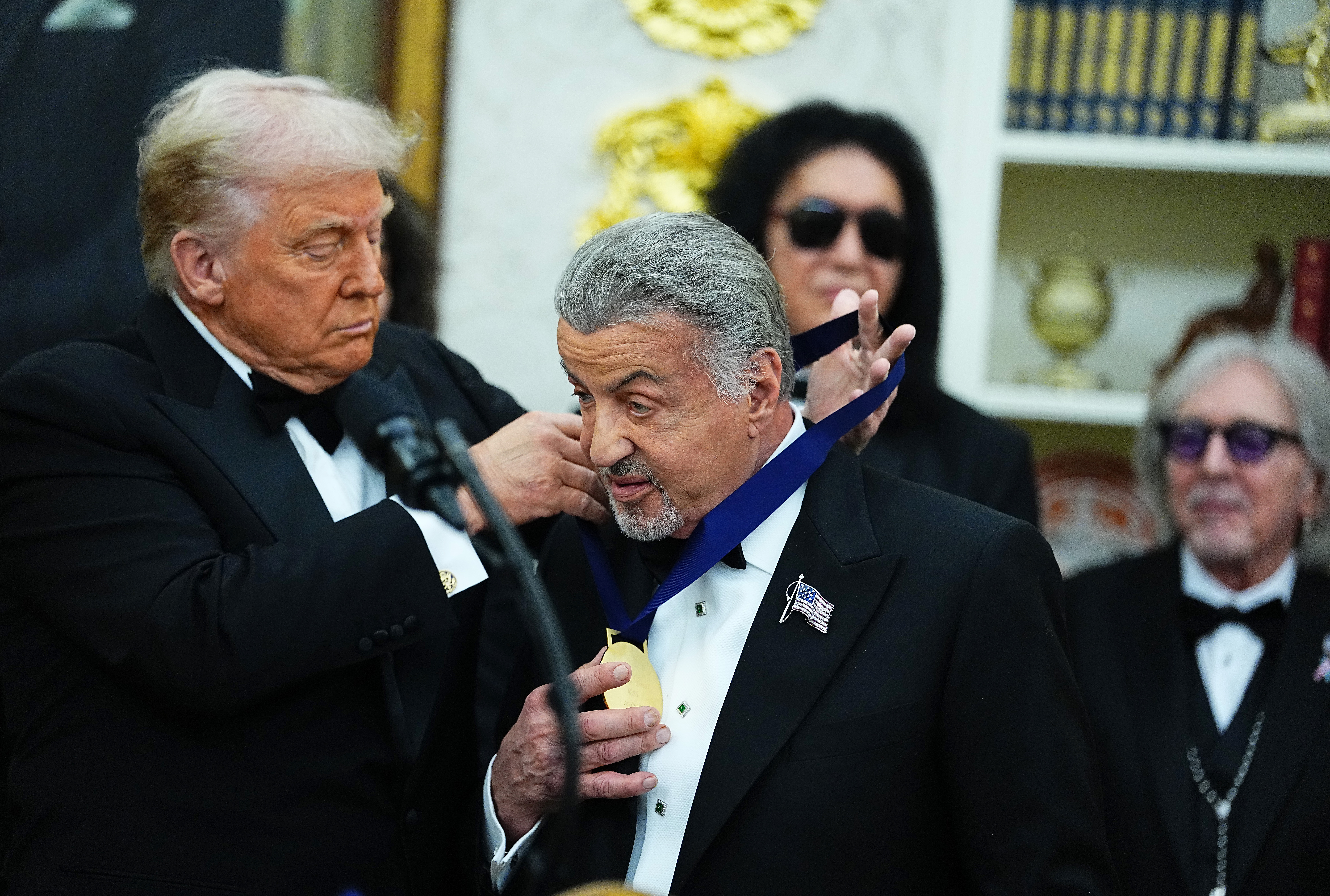 President Donald Trump (L) presents actor Sylvester Stallone (R) a medal for the 2025 Kennedy Center Honorees during a medal presentation in the Oval Office of the White House on December 06, 2025 in Washington, DC