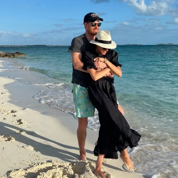 Prince Harry embracing Meghan Markle on a beach.