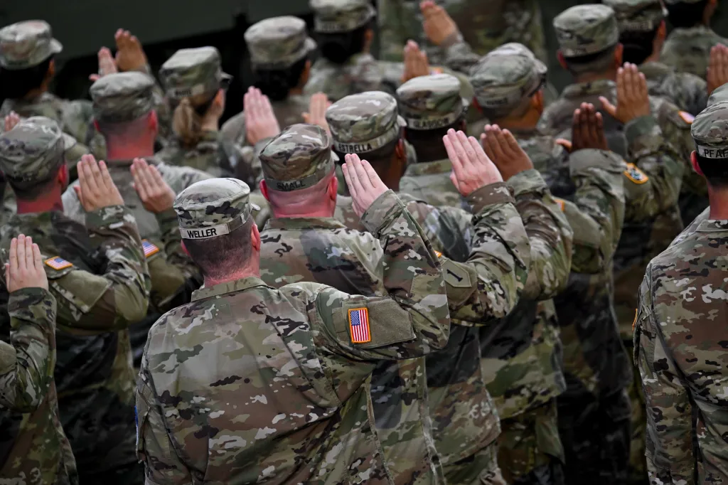 Military members in camouflage uniforms with their hands raised during the US Army's 250th Anniversary Parade.