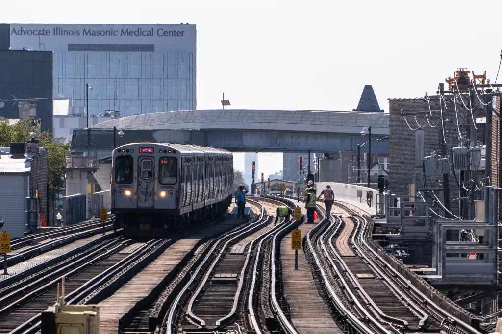 A red line CTA train is seen near workers during construction on the Red and Purple Modernization initiative in Chicago.