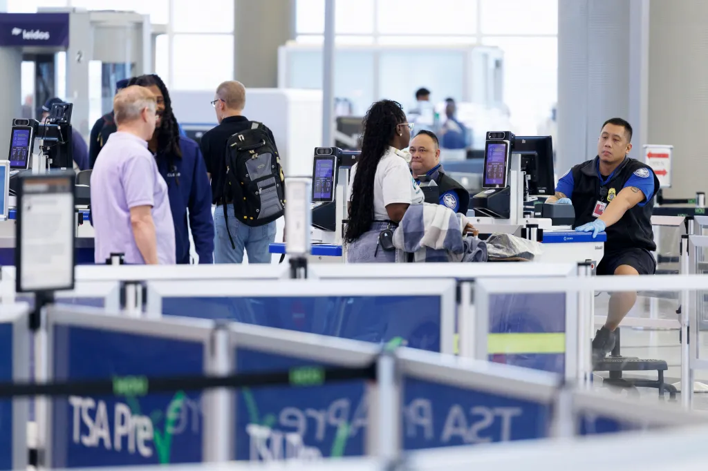 TSA agents checking in passengers at an airport security checkpoint.