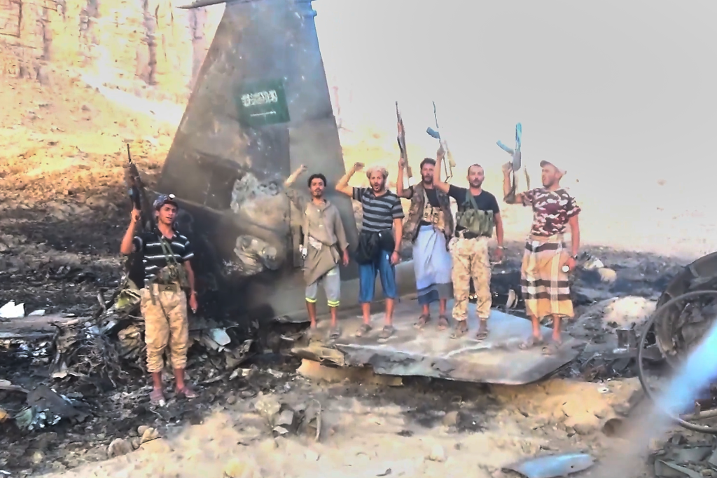 Houthi fighters pose with rifles atop the wreckage of a downed Saudi F-15 fighter jet in Marib province, Yemen.