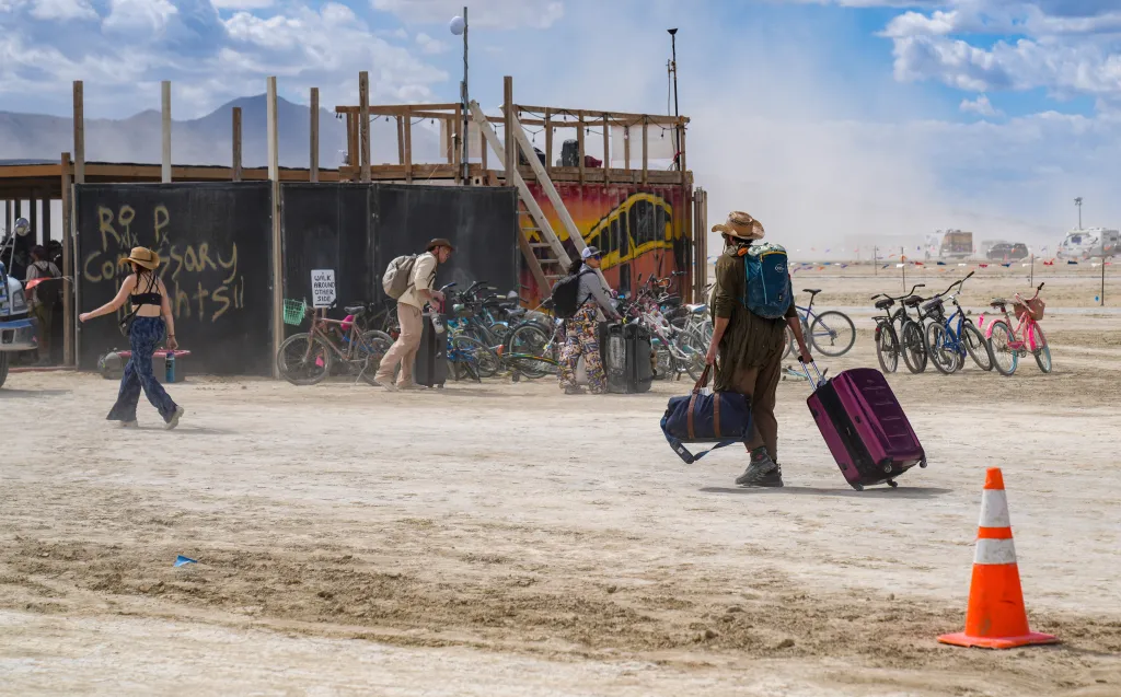 Burning Man attendees carrying luggage to the Burner Bus shuttle.