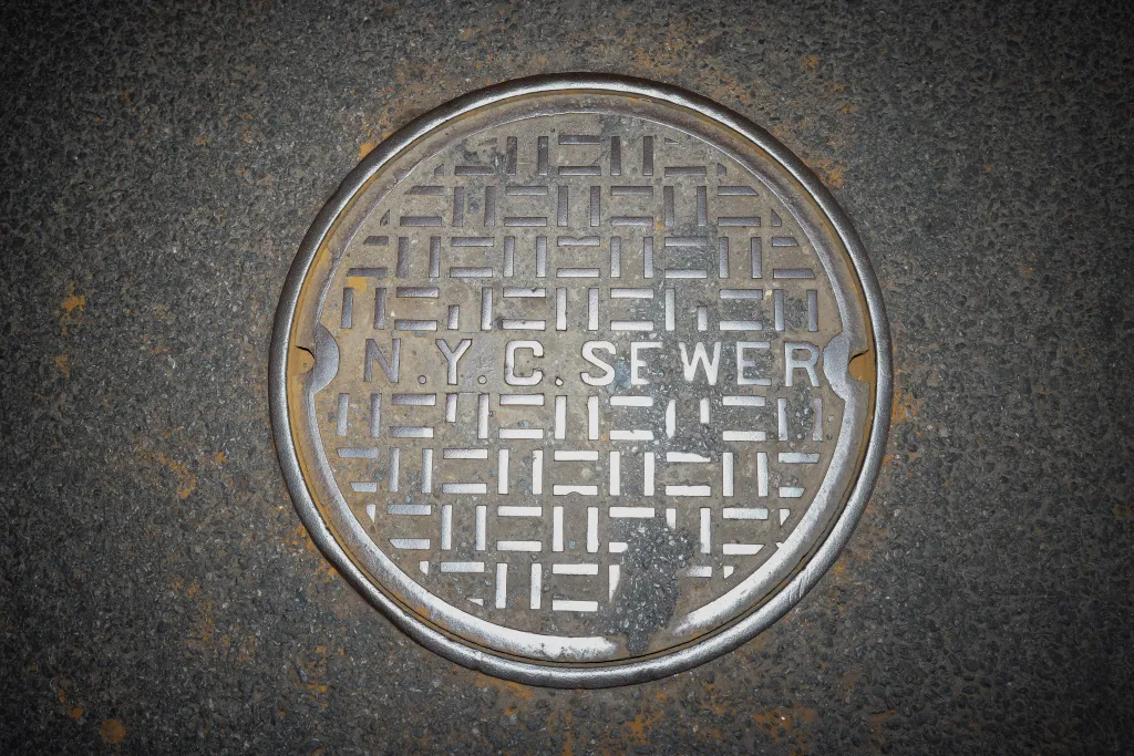 A round metal manhole cover with a geometric pattern and the words