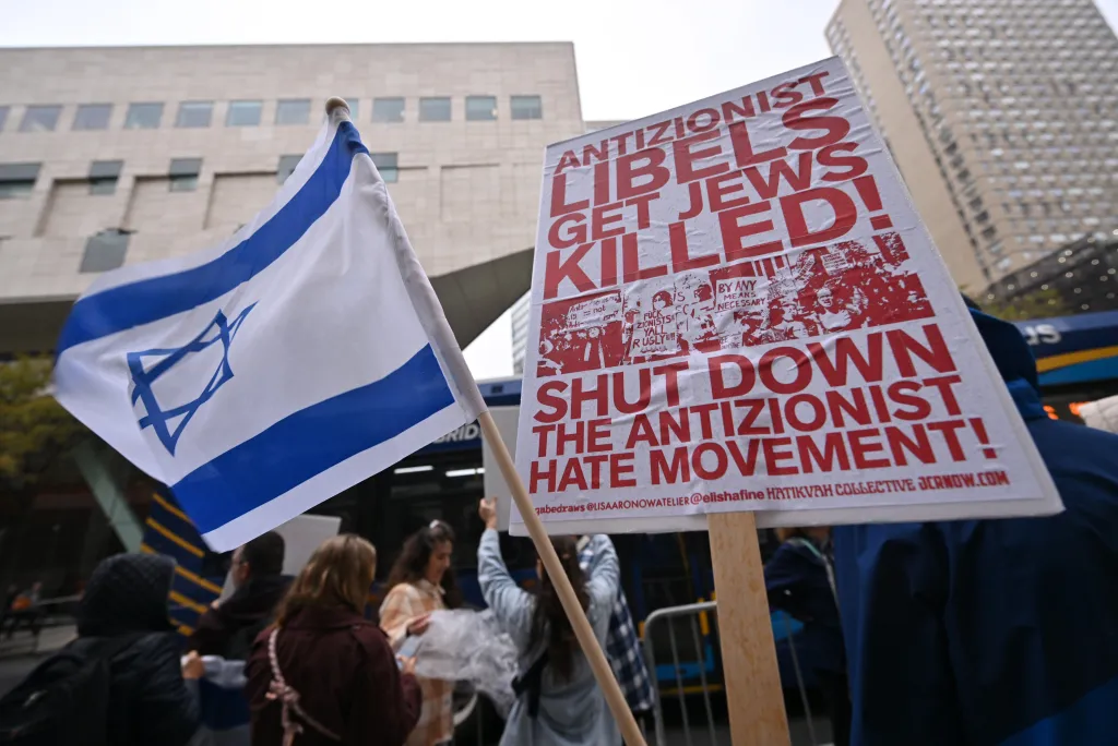 An Israeli flag and a protest sign reading
