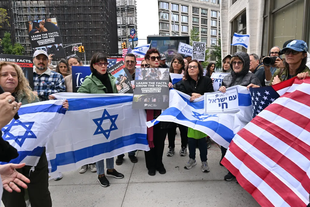 Pro-Israel supporters hold Israeli and American flags and signs stating