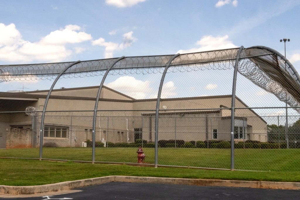 Exterior of the Metro Youth Detention Center, showing a chain-link fence topped with razor wire.