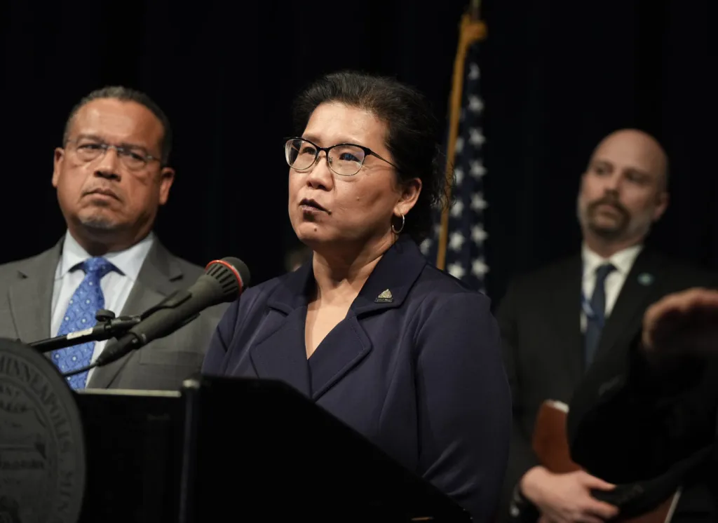 St. Paul Mayor Kaohly Her speaking at a podium with Minnesota Attorney General Keith Ellison standing to her left.