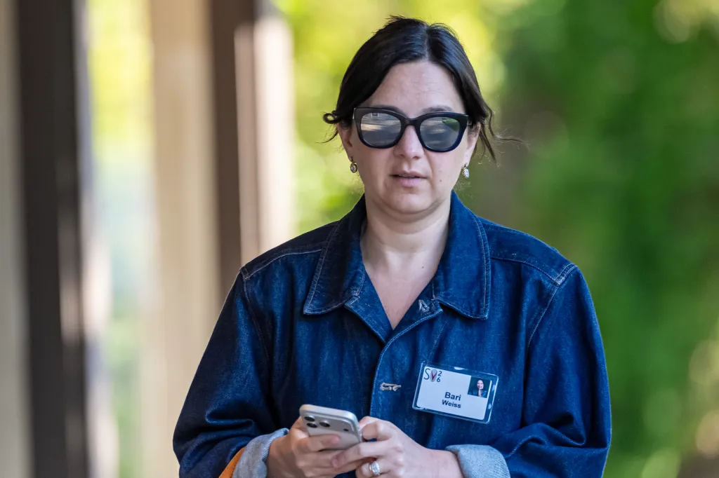 Bari Weiss, editor-in-chief of CBS News, wears a denim jacket and sunglasses while holding a phone at the Allen & Co. Media and Technology Conference.