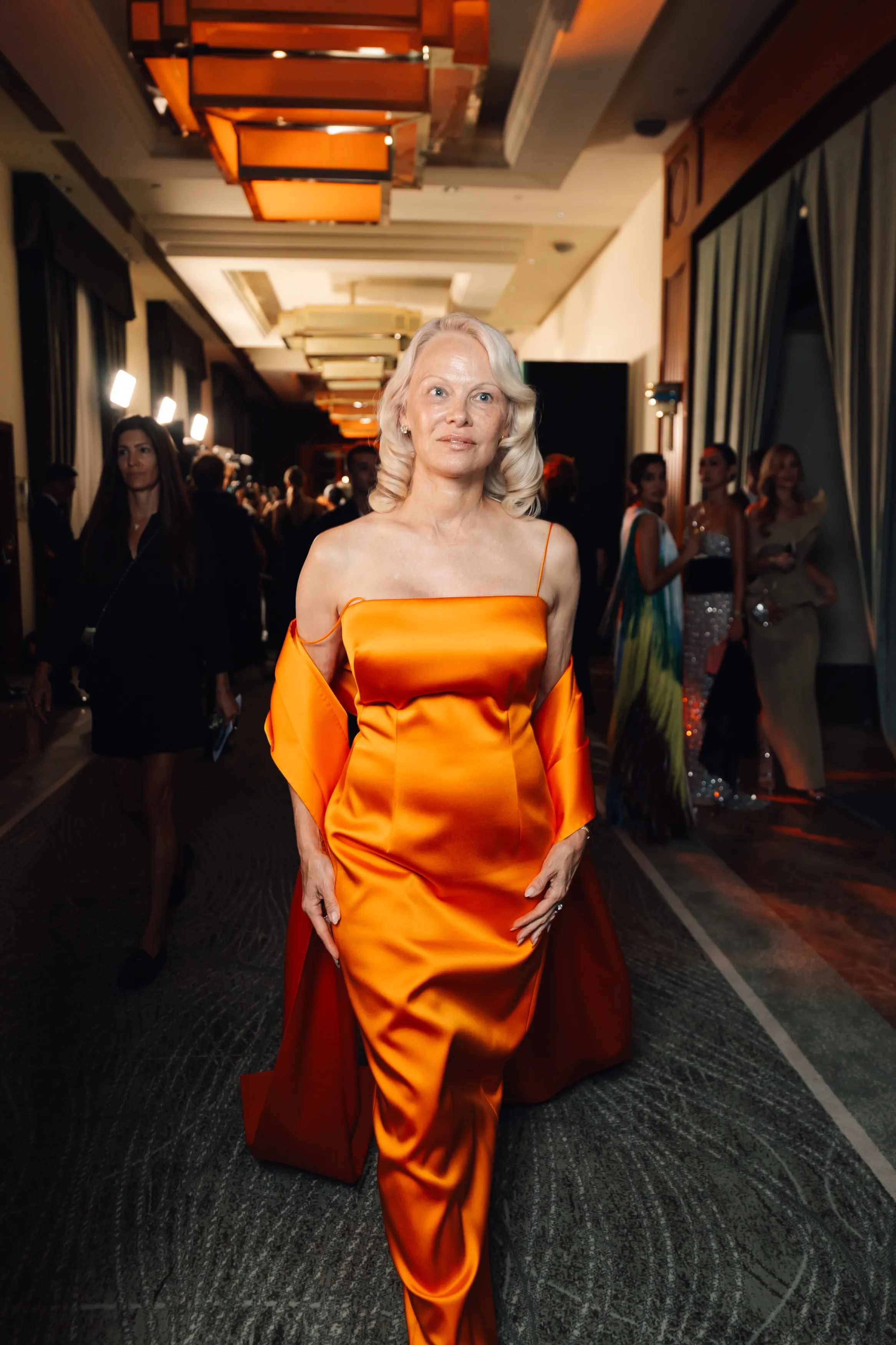 Pamela Anderson in a custom orange Calvin Klein dress at the amfAR Venice 2026 event.