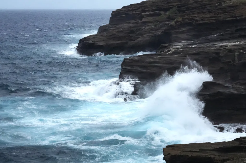 Large waves crashing against a rocky shoreline in Hawaii.