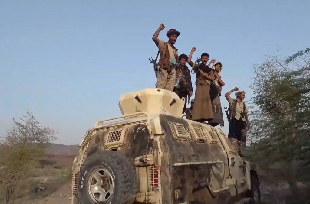 Houthi fighters gesturing on an armored personnel carrier in Mokha, Yemen.
