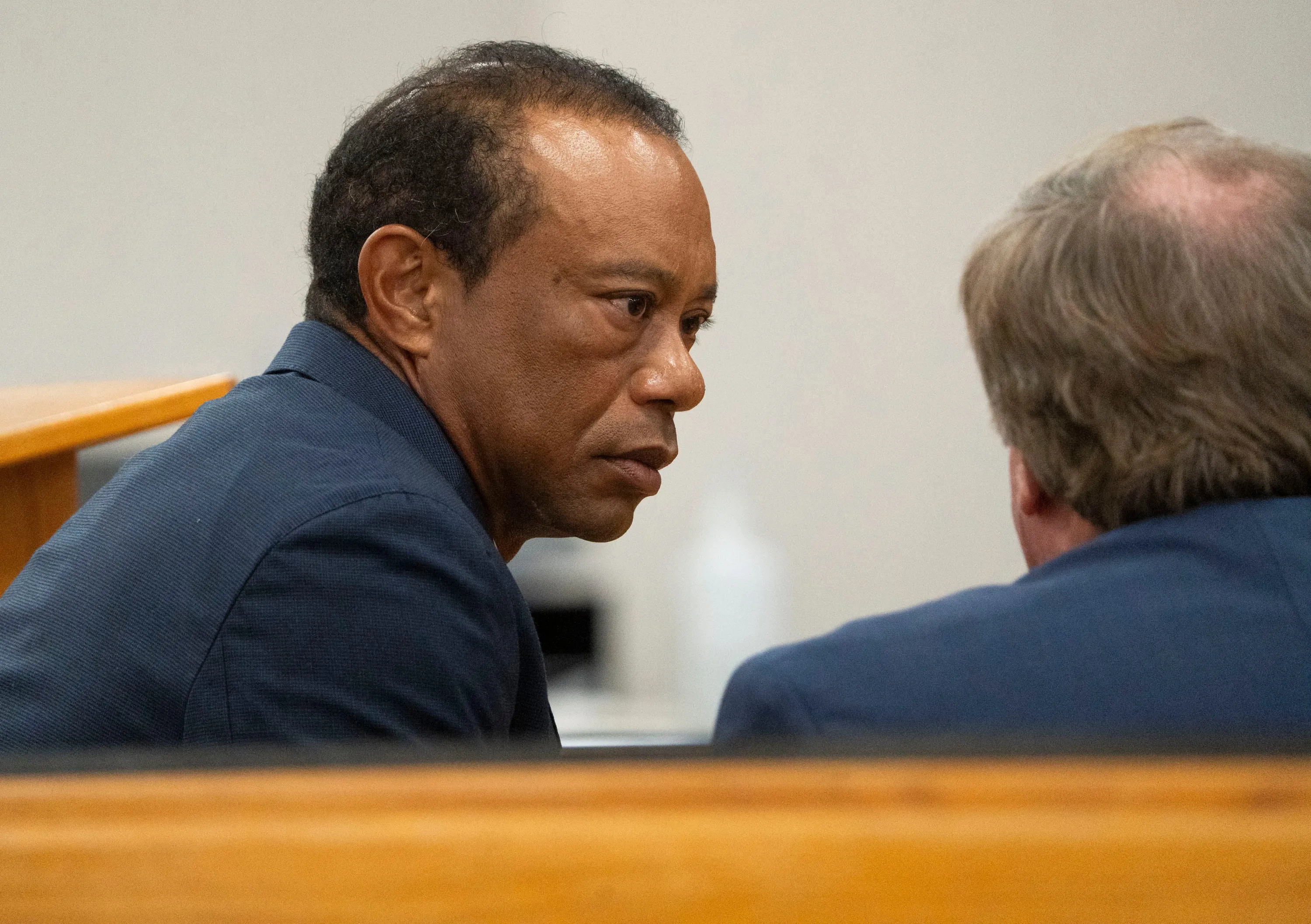 Tiger Woods sitting at a table in a courtroom.