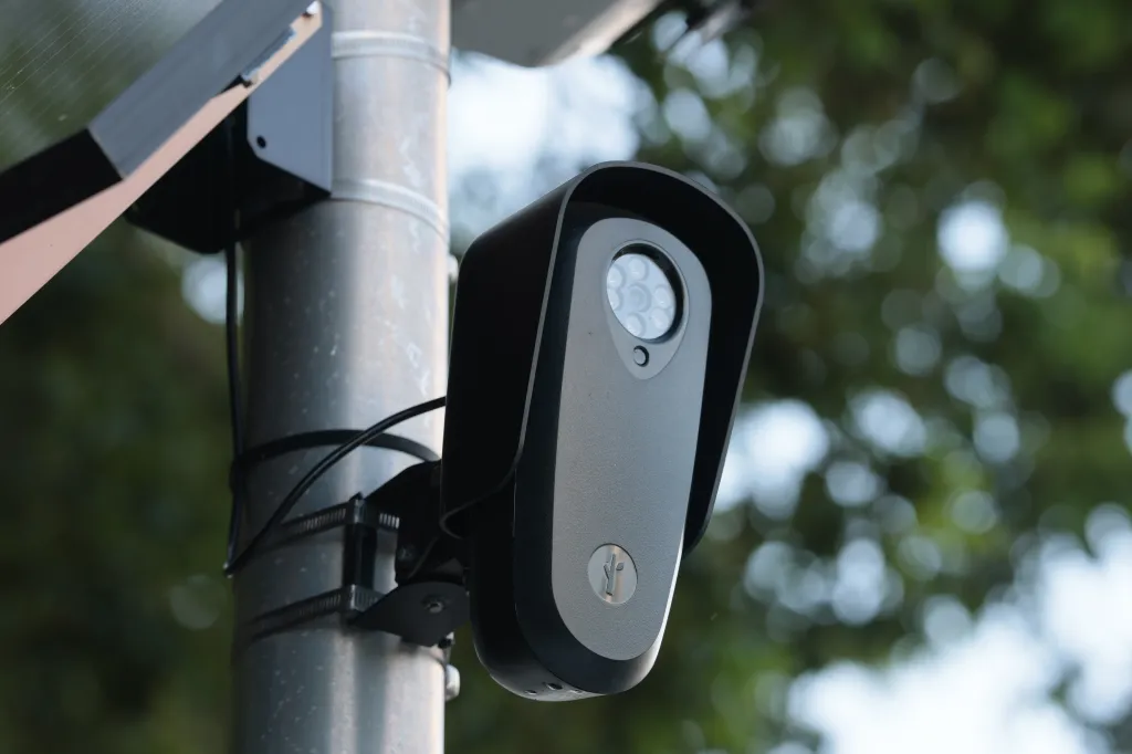 A close-up of a Flock camera attached to a pole.