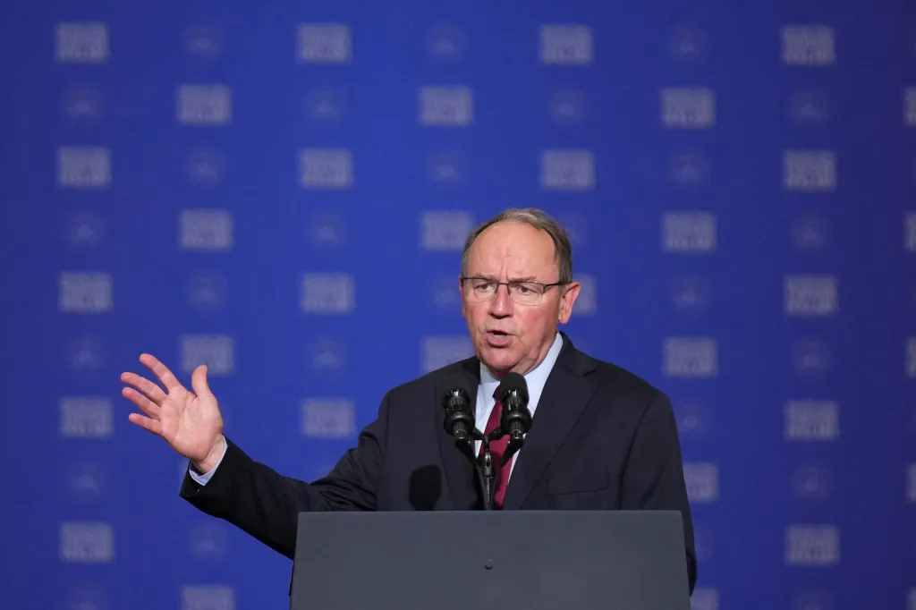 Rep. Tom Tiffany speaks at a podium with a blue background.