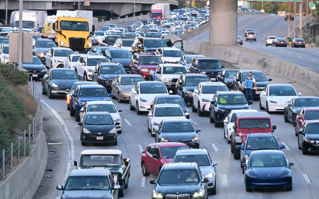 A man stands next to his car in a traffic jam on a Los Angeles freeway.